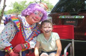 Clown with face-painted child at KidStuff event